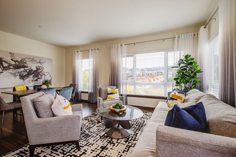 A living room with a grey couch, a grey armchair, a coffee table, and a large painting on the wall.